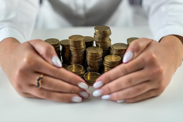 Mãos de uma mulher em uma mesa espelhada com uma montanha-russa com moedas abraçando dinheiro