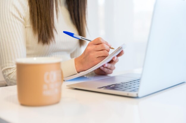 Mãos de uma mulher que trabalha com um computador sentado em casa com a agenda de negócios através do home office teletrabalho