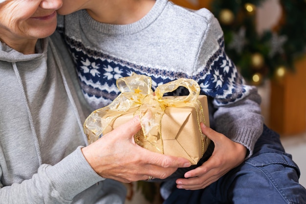 Mãos de uma mulher sênior e uma criança segurando o presente de Natal