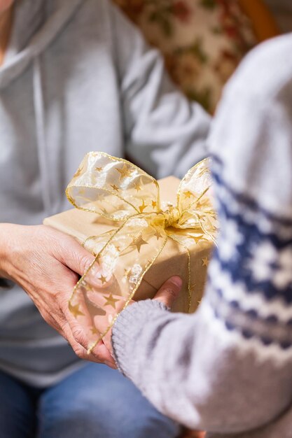 Mãos de uma mulher sênior e uma criança segurando o presente de natal