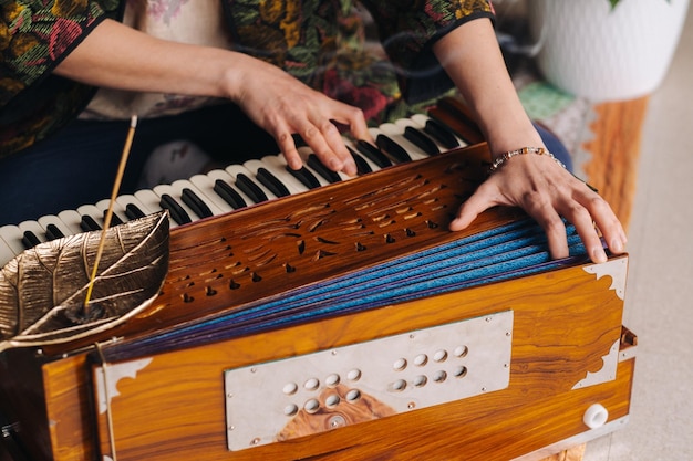 Mãos de uma mulher sentada no chão e tocando harmônio durante a prática de kundalini yoga