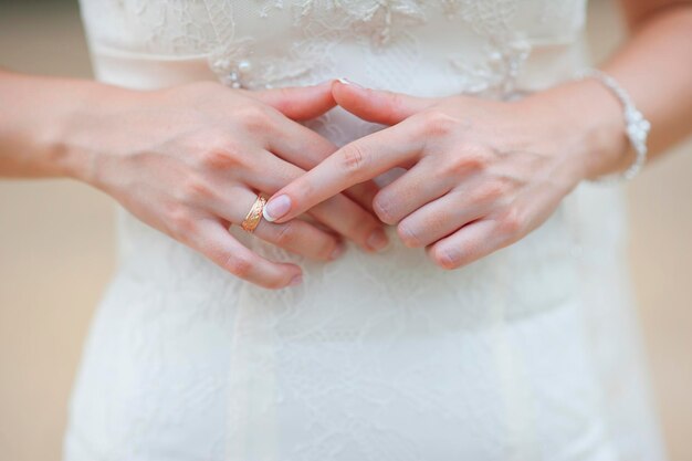 Mãos de uma noiva em um casamento apontando para o anel de ouro