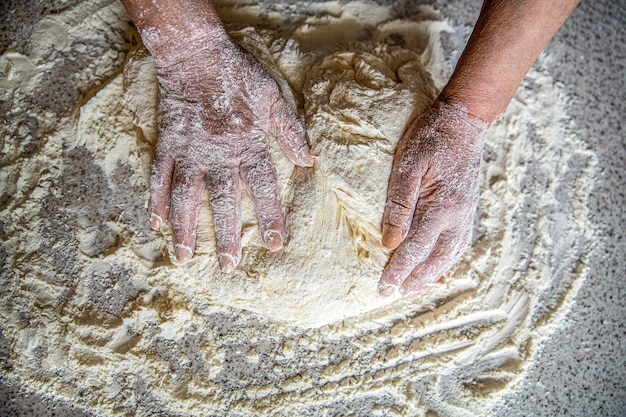 Mãos de velhas mulheres processam a massa para o pão de trigo Preparação de massas Preparações de massas