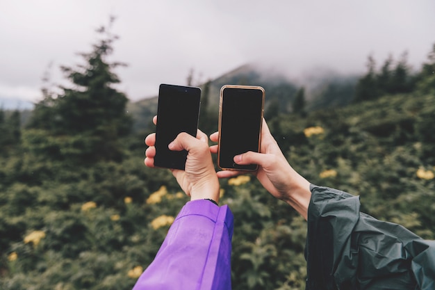 Mãos de viajantes com smartphones tiram foto da natureza paisagem vista em dia chuvoso de verão