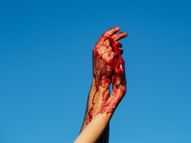 Foto mãos de zumbi sangrentas com sangue vermelho no céu azul