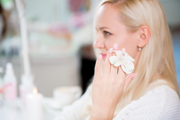 Mãos delicadas de beleza com manicure segurando a flor de lírio.