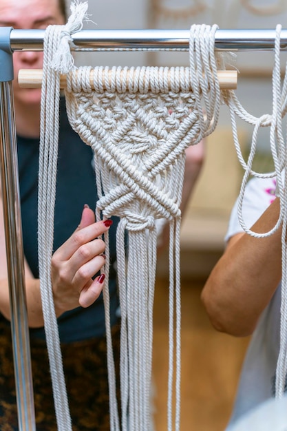 Mãos delicadas de mulher fazendo macramê branco