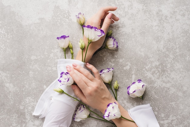 Mãos delicadas de uma mulher com flores nuas manicure e eustoma.