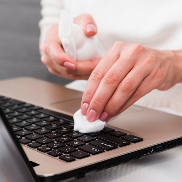 Foto mãos desinfetando teclado de laptop