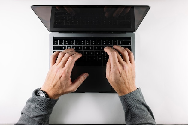 Mãos digitando em um laptop cinza