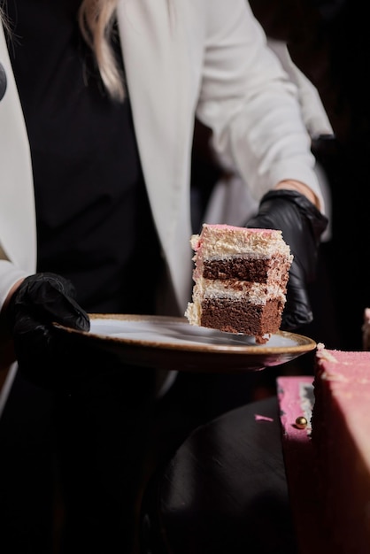 Mãos do chef em luvas de látex pretas cortando bolo de chocolate