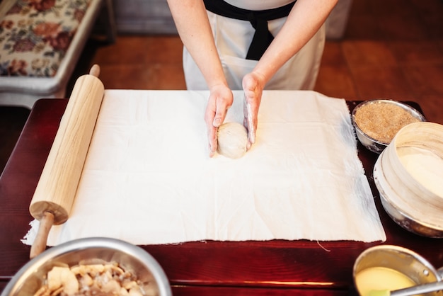 Mãos do chef masculino e massa na mesa de madeira. Strudel caseiro