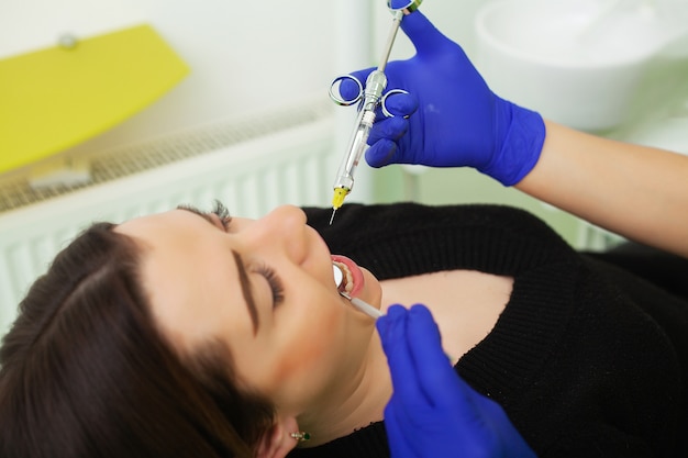 Mãos do dentista segurando a ferramenta e seringa nas mãos