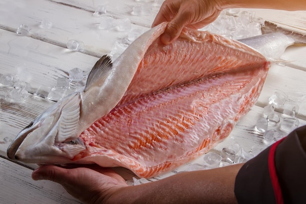 Mãos do homem tocando peixe cru com carne vermelha o chef limpou o salmão, o melhor peixe para sushi