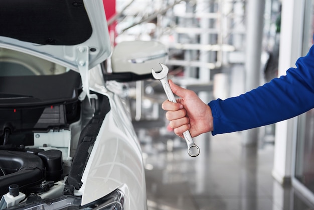 Mãos do mecânico de automóveis com chave na garagem