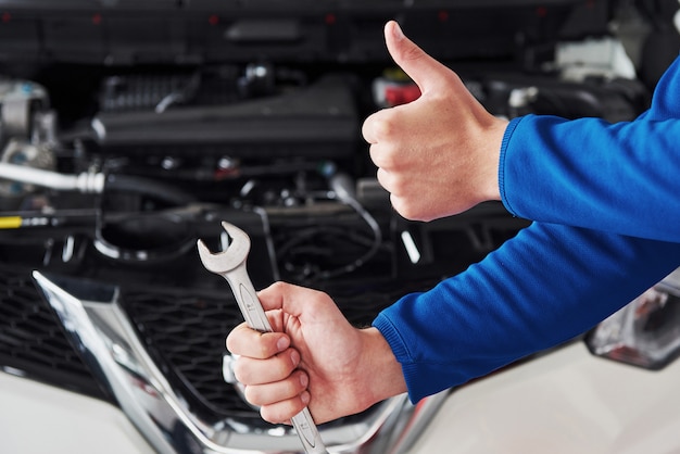 Foto mãos do mecânico de automóveis com chave na garagem