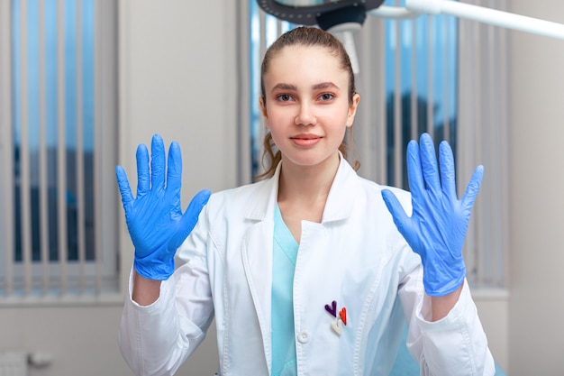 Mãos do médico calçando luvas de látex em um hospital. mulher com um avental de médico com luvas de látex. proteção contra vírus e bactérias.