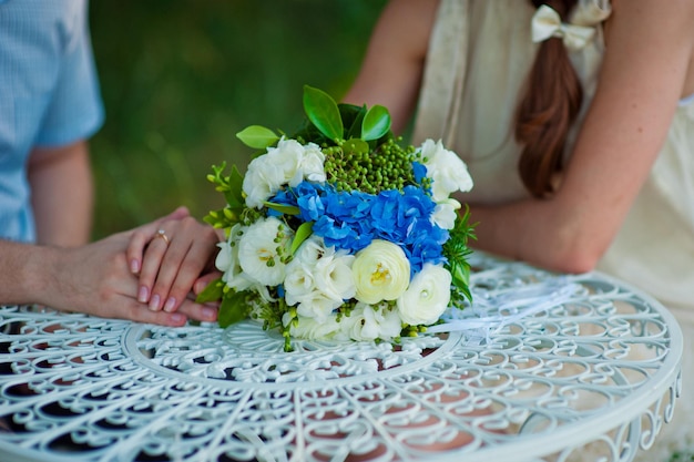 Mãos do noivo e buquê de casamento em uma mesa