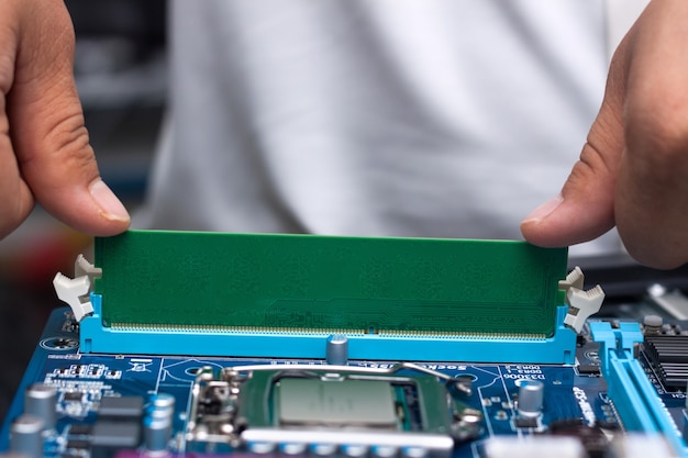 Mãos do técnico instalando a memória do usuário na placa-mãe de um computador