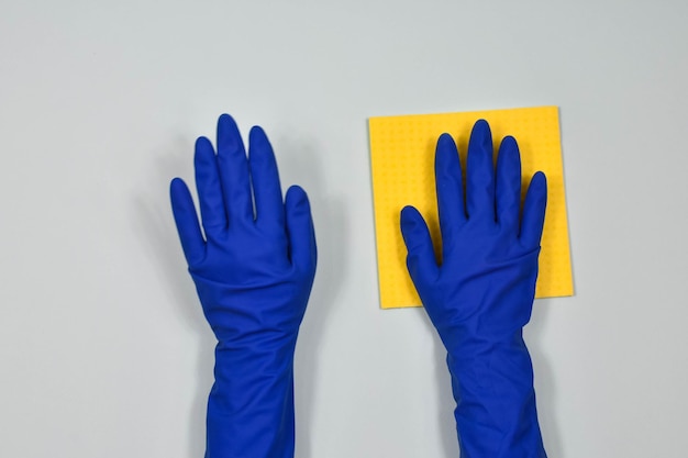 Mãos do trabalhador em luvas protetoras de borracha com um pano limpando a superfície de uma mesa ou parede em uma sala banheiro cozinha Início da primavera ou limpeza regular