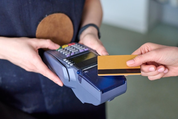 Mãos do vendedor segurando o leitor de cartão durante o pagamento sem contato