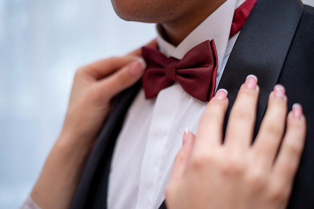 Mãos dos noivos em uma gravata borboleta no dia do casamento