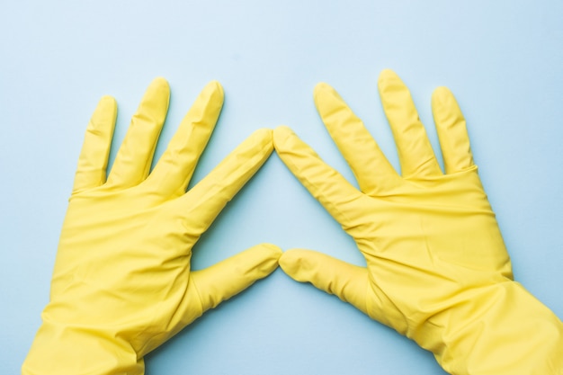 Mãos em luvas amarelas para limpeza na superfície azul
