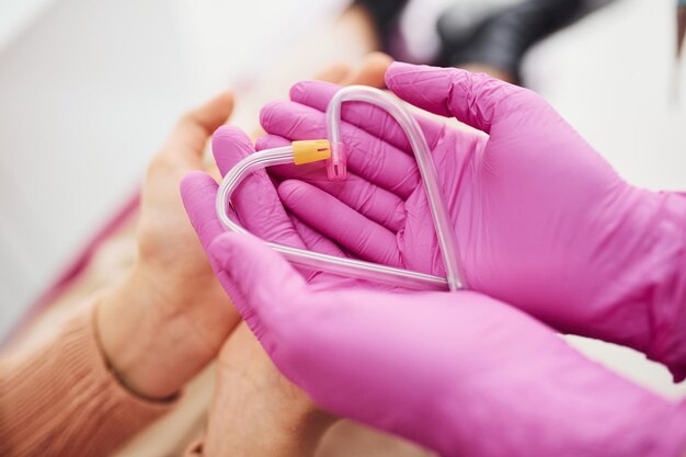Mãos em luvas segurando tubos clínicos em forma de coração