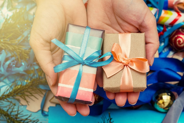 Mãos em um suéter tricotado segurando a caixa de presente. Conceito de preparação de férias de Natal.