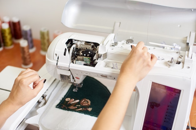 Mãos enchendo o fio na máquina de costura