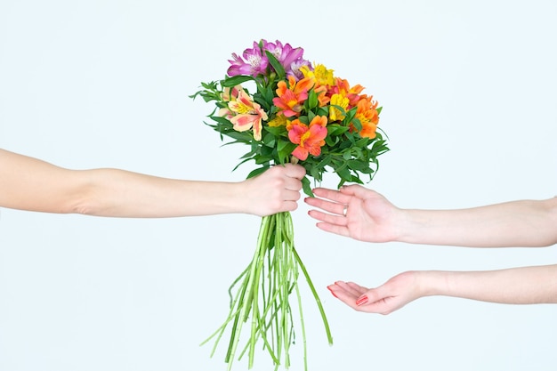 mãos entregando um buquê de flores de alstroemeria