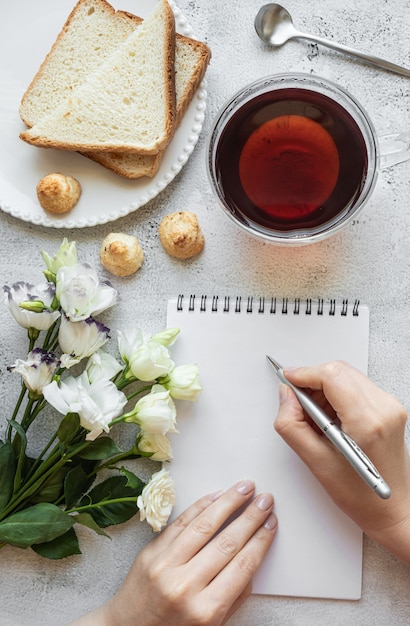 Mãos escrevendo em um bloco de notas para o café da manhã