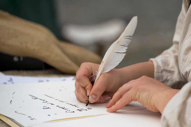 Foto mãos escrevendo uma carta com uma pluma