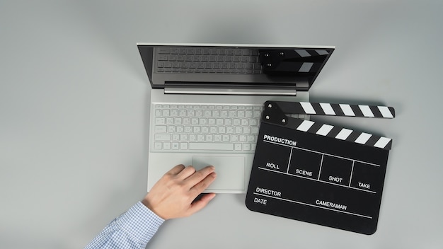 Mãos está digitando e computador laptop ou notebook com claquete preta ou filme ardósia sobre fundo cinza. Vista de olho do Studio shot.top.