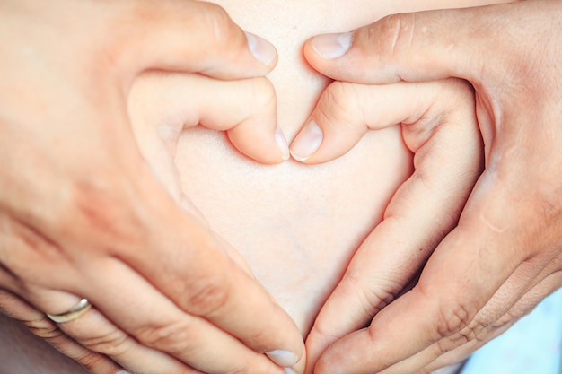 Mãos fazem coração na barriga