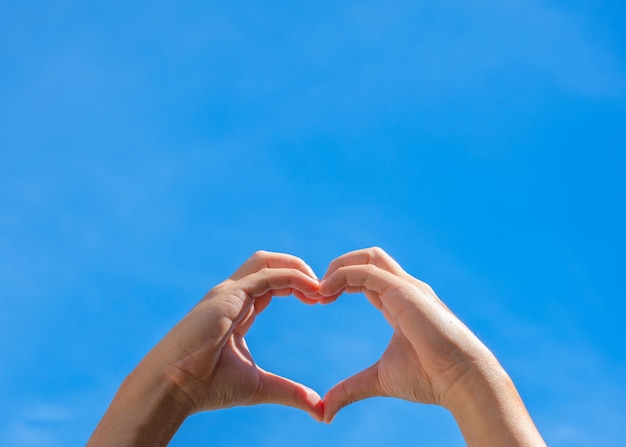 Mãos fazendo forma de coração contra o céu Conceito de amizade de amor