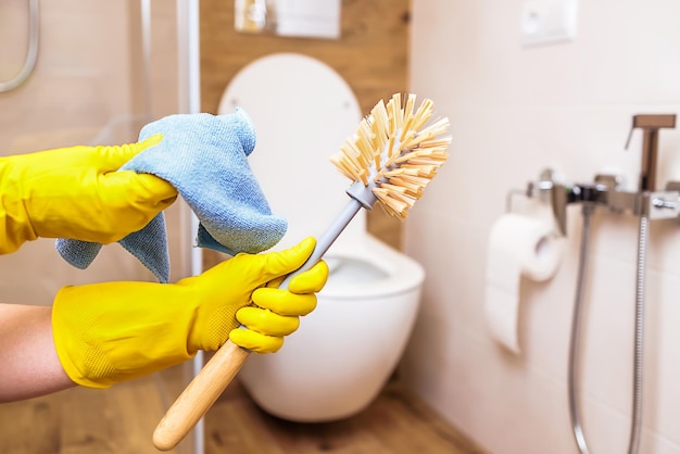 Foto mãos fechadas em luvas com equipamento para limpeza higiênica do banheiro