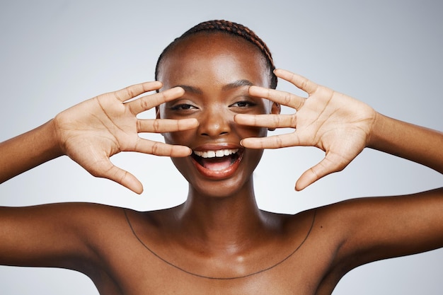 Mãos felizes e retrato de mulher negra para beleza de cuidados com a pele revelados e animados em um fundo de estúdio Sorria jovem e uma pessoa africana com um gesto para a pele facial limpa ou um brilho dermatológico