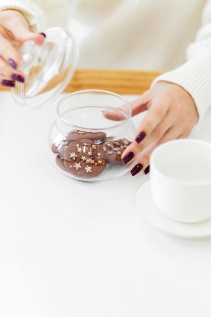 Mãos femininas abrem uma jarra de vidro com biscoitos de Natal