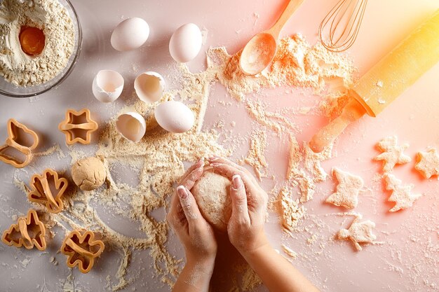 Mãos femininas amassam massa com ovo e um rolo para preparação de biscoitos Vista superior Explosão solar