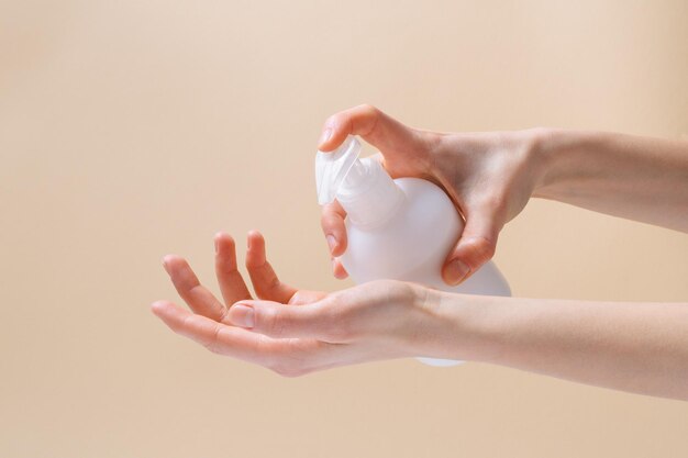 Mãos femininas aplicando creme para a pele em fundo bege liso O conceito de beleza e cosméticos naturais para cuidados Imagem para o seu design