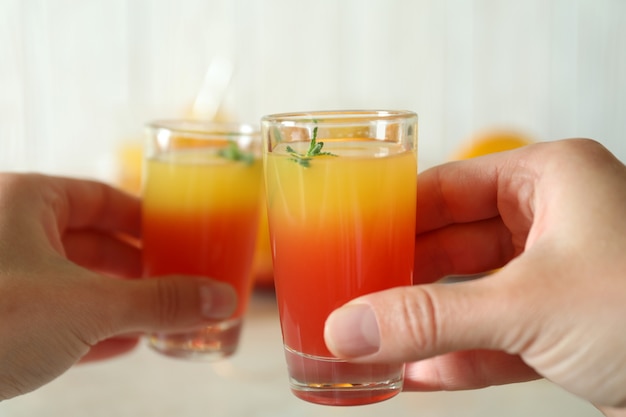 Mãos femininas brindam com Tequila Sunrise, close-up