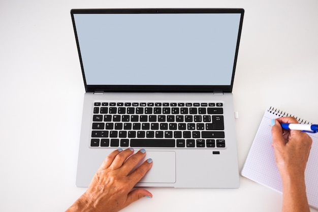 Mãos femininas caucasianas navegando no laptop enquanto escreve à mão no caderno espaço de cópia de tela em branco