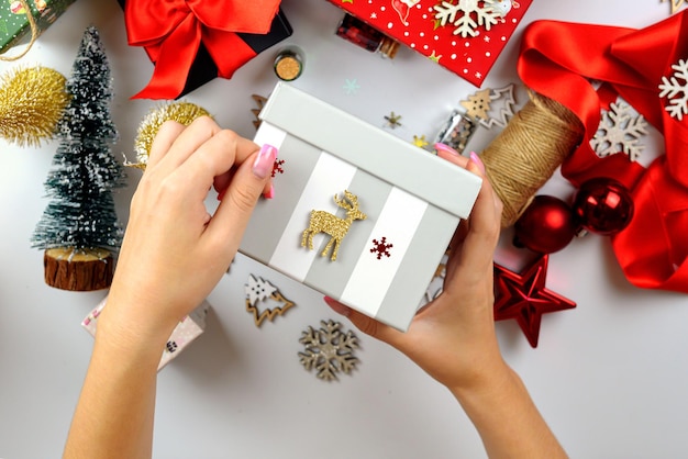 mãos femininas closeup embalando presentes de Natal decoração de Natal feita à mão em cima da mesa