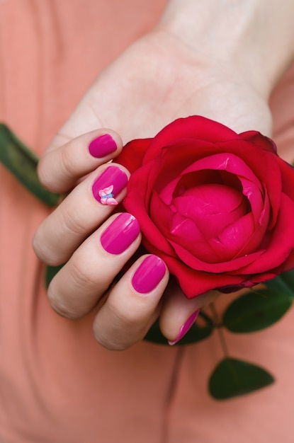 Mãos femininas com arte de unha rosa.