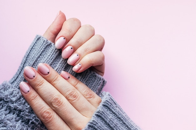 Mãos femininas com bela manicure - unhas nude rosa com pontos