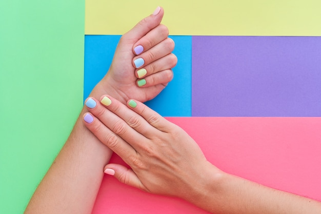 Mãos femininas com cores brilhantes em um fundo colorido