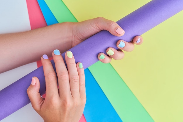 Mãos femininas com cores brilhantes em um fundo colorido