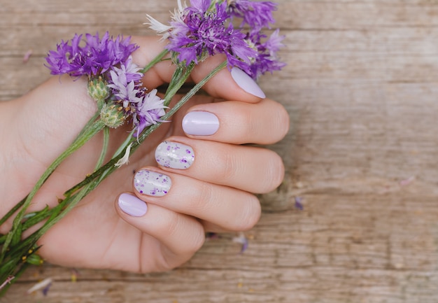 Mãos femininas com design de unhas roxas