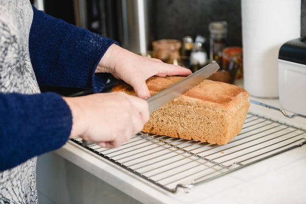 Mãos femininas com faca cortam pão fresco